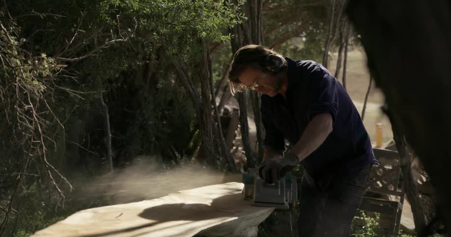A man is using a belt sander to sand a piece of wood