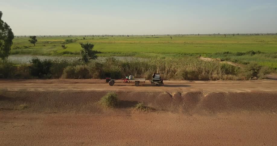 Farm vehicle rolls down a dirt road in the country