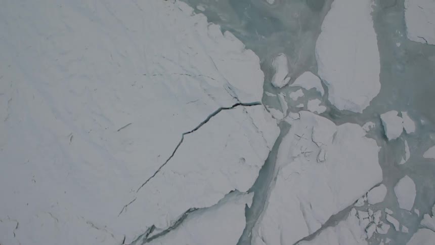 Overhead view of cracks and surface water formations along the glacial ice
