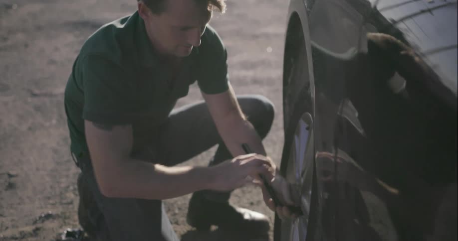 A man removes the lug nuts on a tire