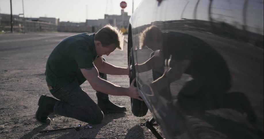 A man is changing a tire on a vehicle