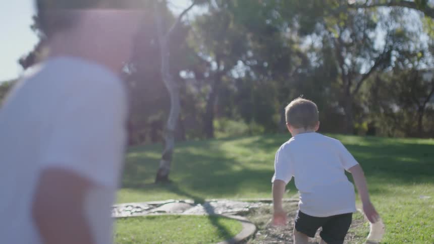 Two boys run under the sun down the trail
