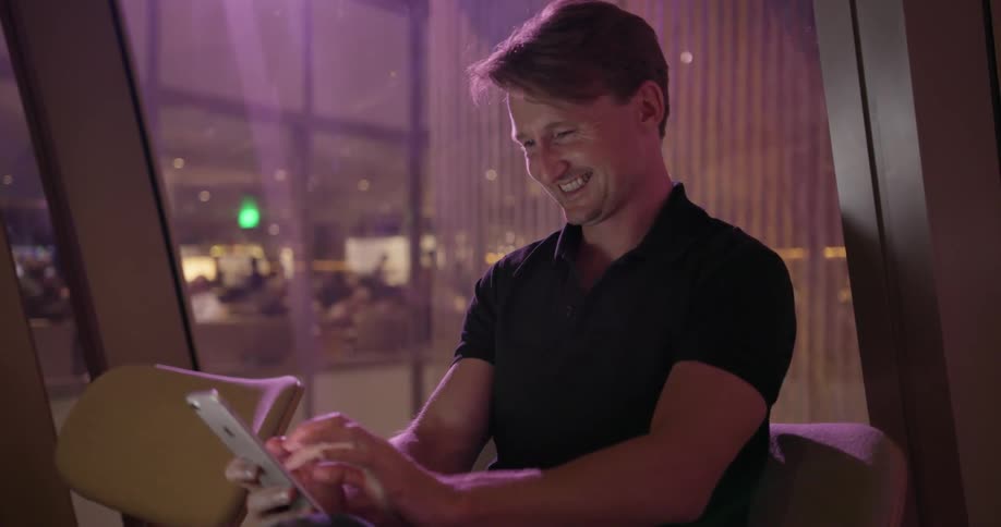 A man laughs as he uses his phone