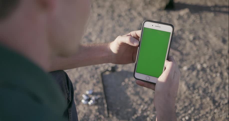 Man looks at his phone outside on a sunny day