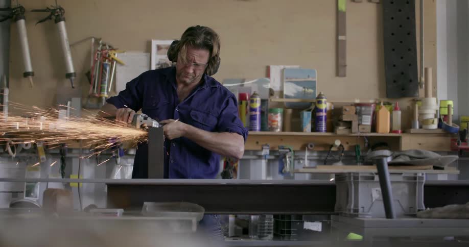 Man grinds a piece of metal as sparks shower around him
