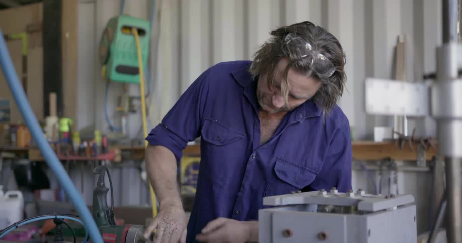 A man works on a tool in a workshop