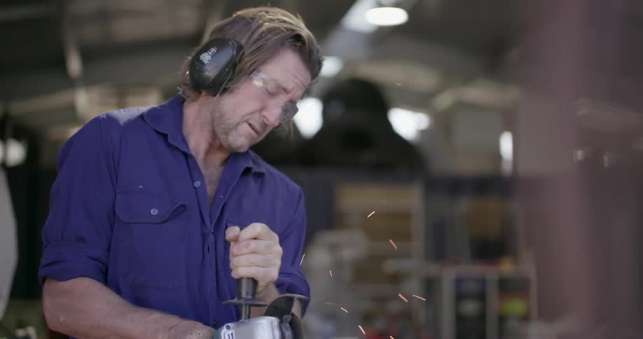 A man uses a power tool in a workshop