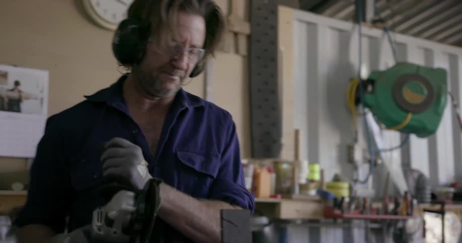 A man uses a power tool in a workshop
