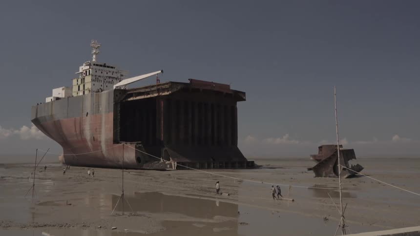 People walk towards a barge being built
