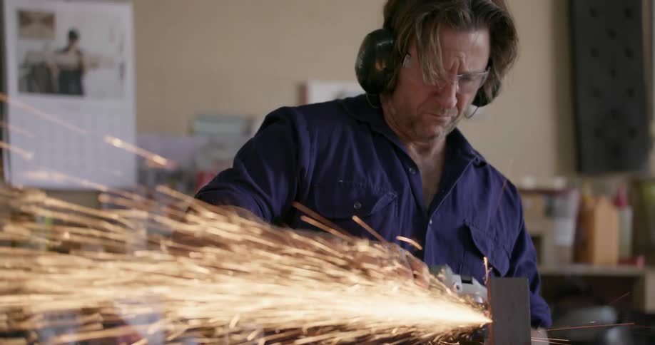 A man cuts a piece of steel in a workshop