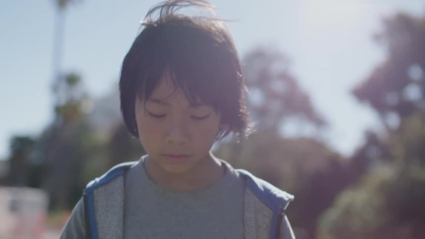 A young boy walks outside under the shining sun