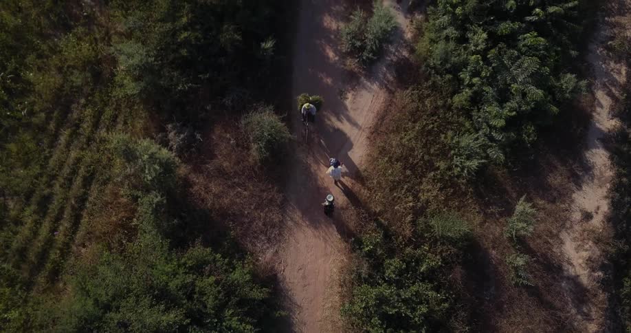 People walk on a dirt path in a rural area