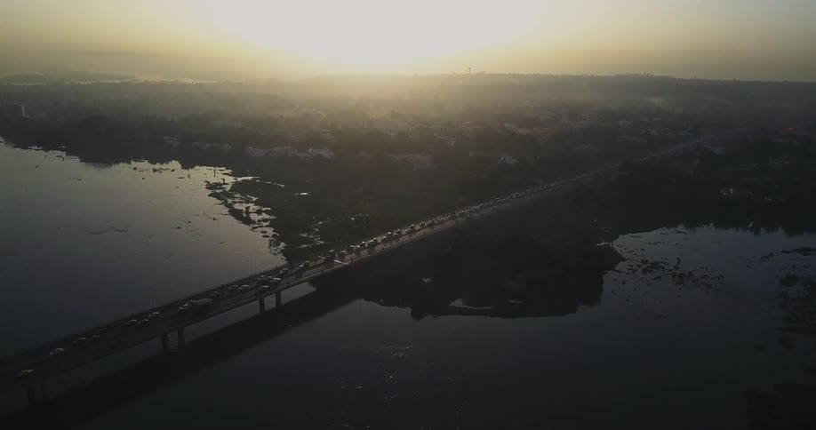 Cars drive over a long bridge at sunset