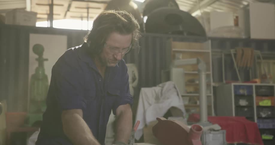 A man pushes a board through a table saw