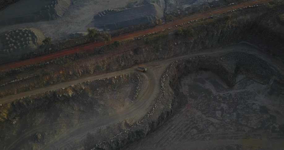 A truck drives on a dirt road in a quarry or mine