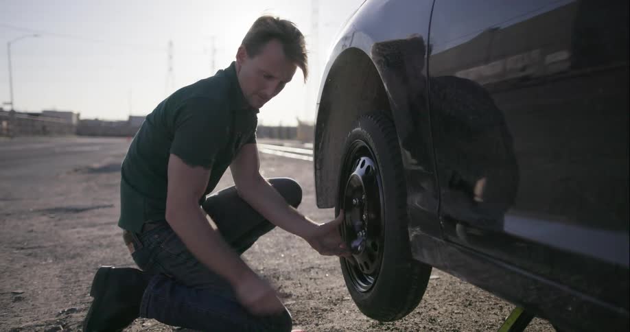 A man is putting on a spare tire