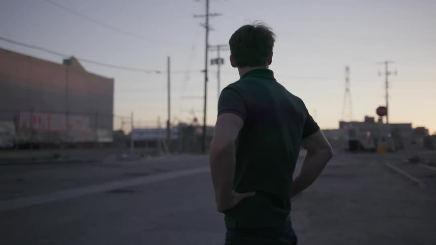 Man stands with hands on his hips looking around at sunset