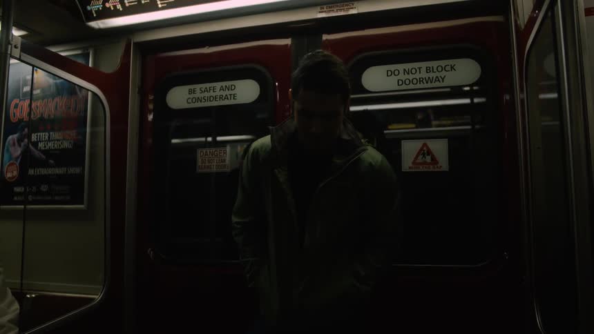 A man leans against the doors of a subway car