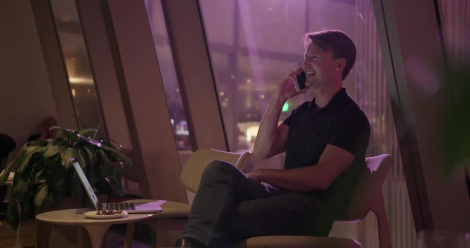 A man sits in a chair talking on the phone