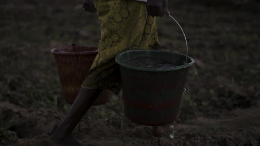 African woman carrying two buckets full of water outdoor