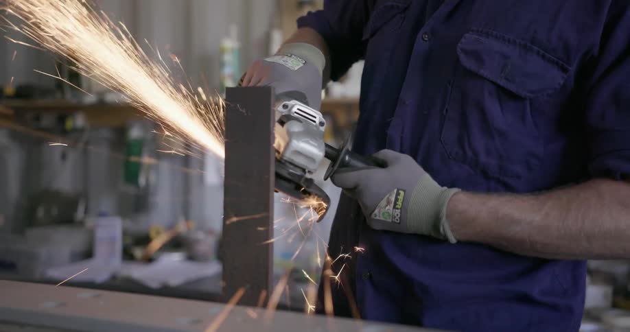 Man grinds a piece of metal as sparks shower around him