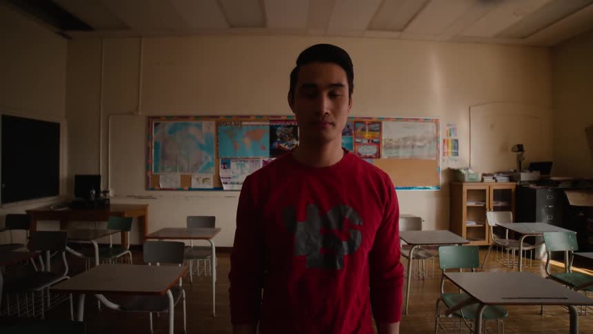 A young man is standing in the middle of a classroom