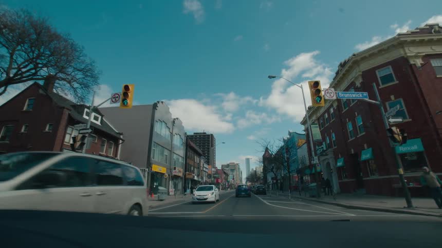 Cars and people travel down the town street on a sunny day