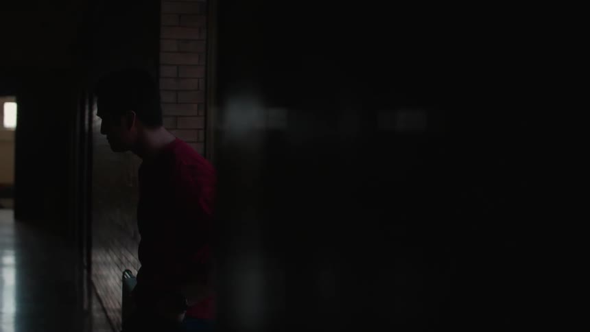 Man leaning on a wall in a dimly lit building