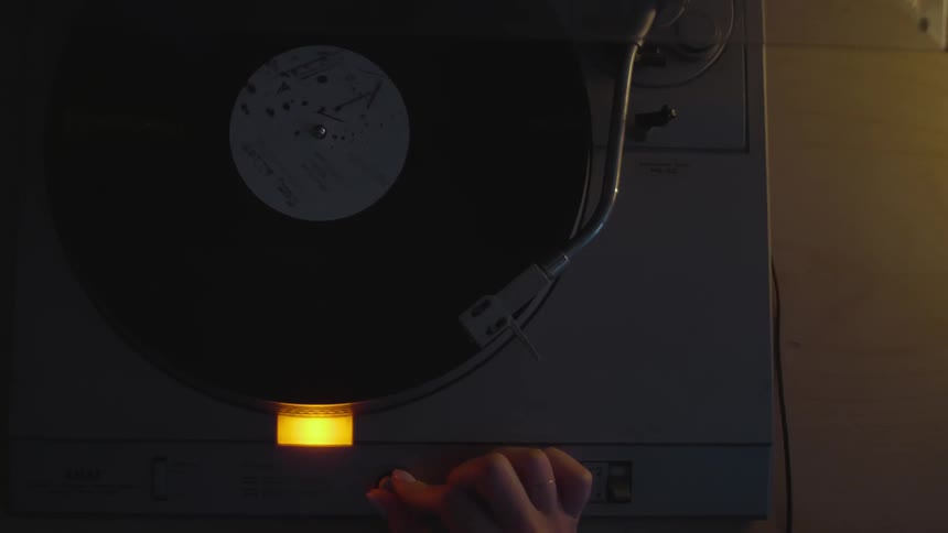 A woman places the needle on an album and turns up the volume