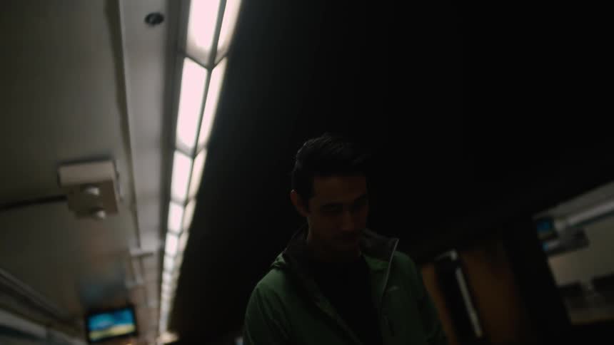 A man is looking at the ground standing next to a subway platform