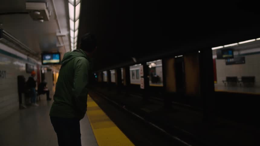 Man in a hoodie waiting for a subway car