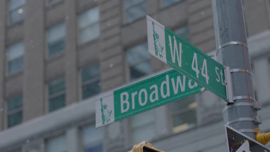 Snow sly falls around a broadway sign