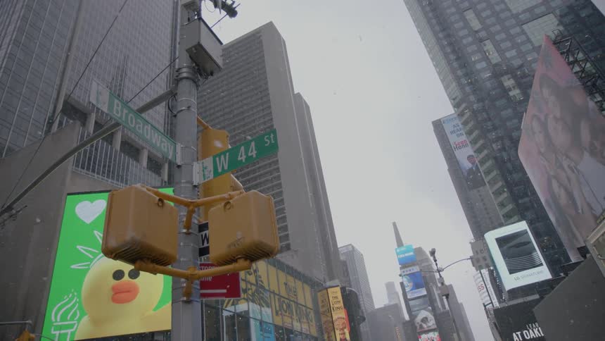 Snow falls and electronic billboards play in times square