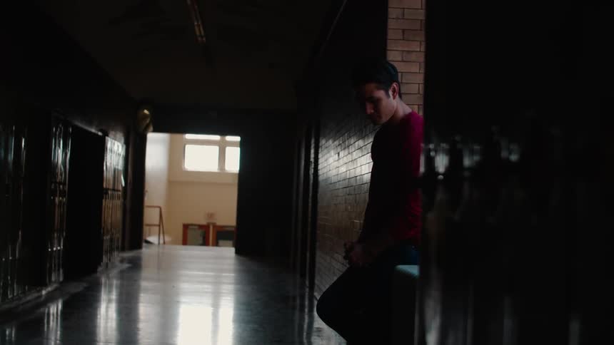 A man stands in a dark school hallway