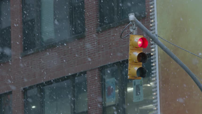 Snow falls as a traffic light changes from red to green