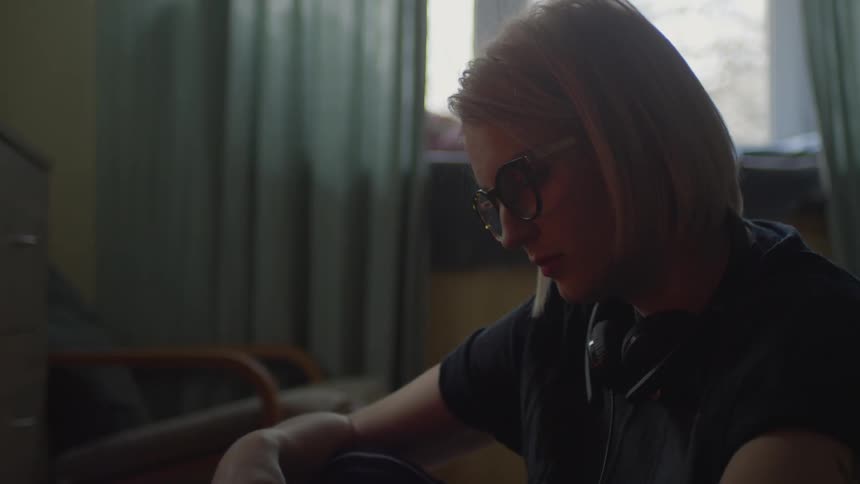A woman is looking down in her bedroom