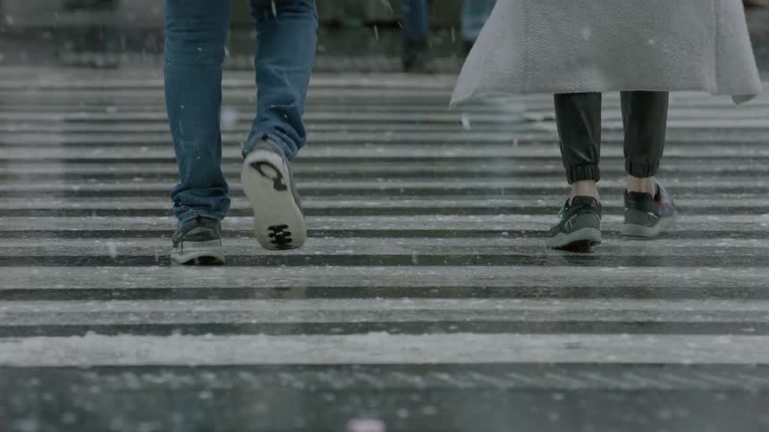 Pedestrians cross an urban street on a snowy day