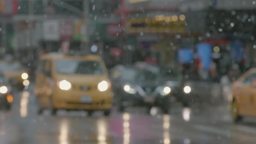 Traffic starts through an intersection in a city as it snows
