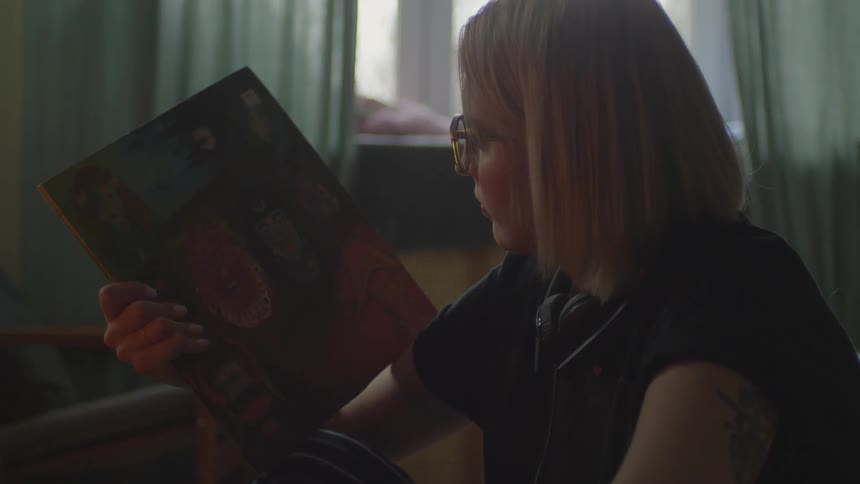 A woman is sitting by the window looking down