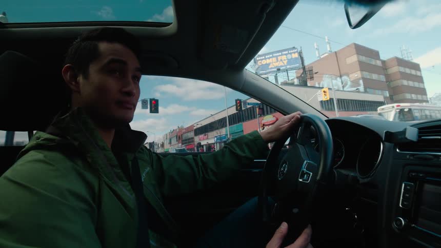 Man driving a car in a large city as seen from the passenger seat area