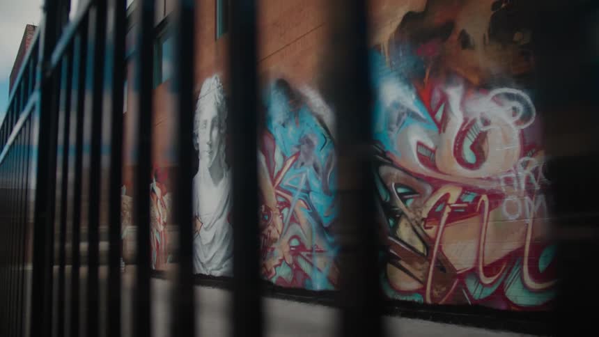 Large wall behind fence covered in graffiti art