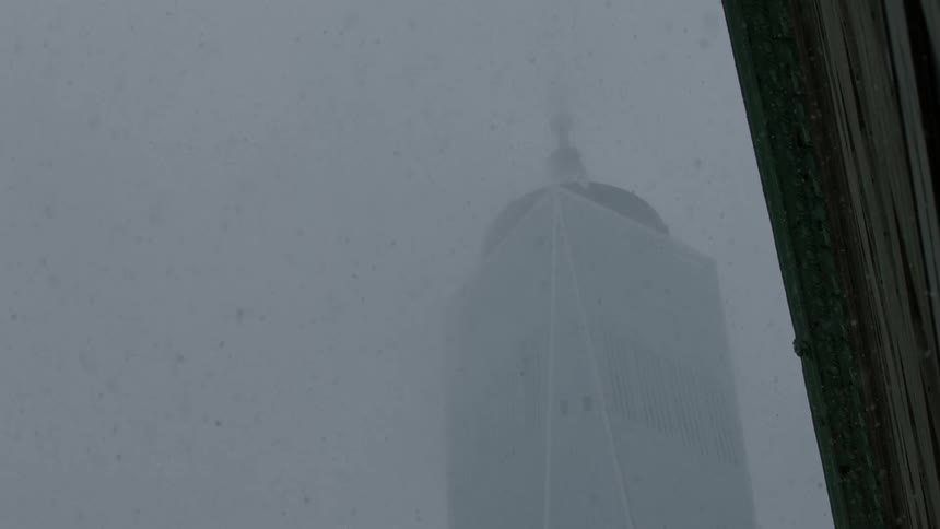 Snow falls around a city skyscraper