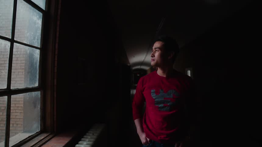 A man sighs deeply as he stares out of a window