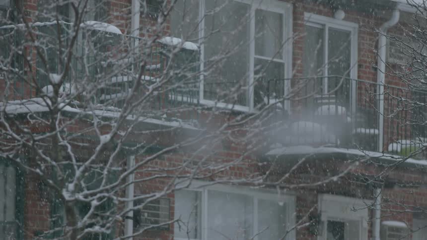 Snow falls in front of an apartment building