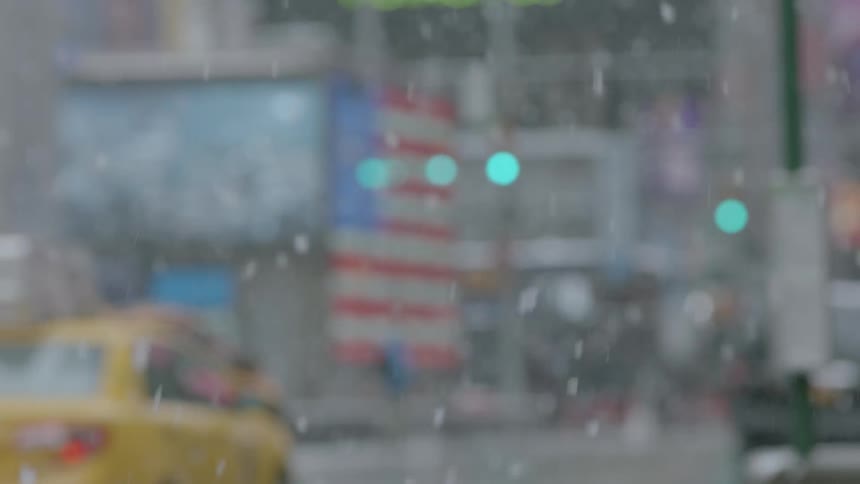 Snow falls around traffic in a city