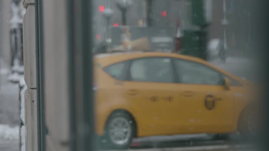Traffic and pedestrians travel in a city on a snowy day