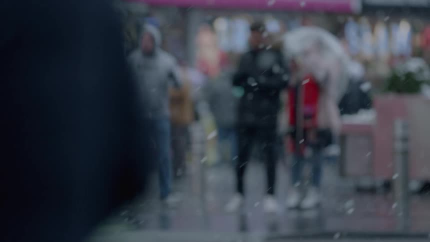 People travel down the street as it snows