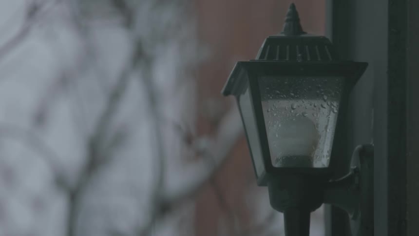 The rain slowly falls on the street lamp
