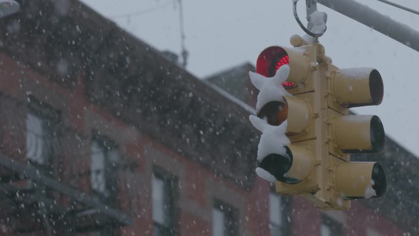 The snow is falling covering the street light