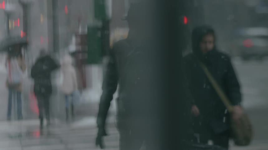 Pedestrians walk in a city on a snowy day
